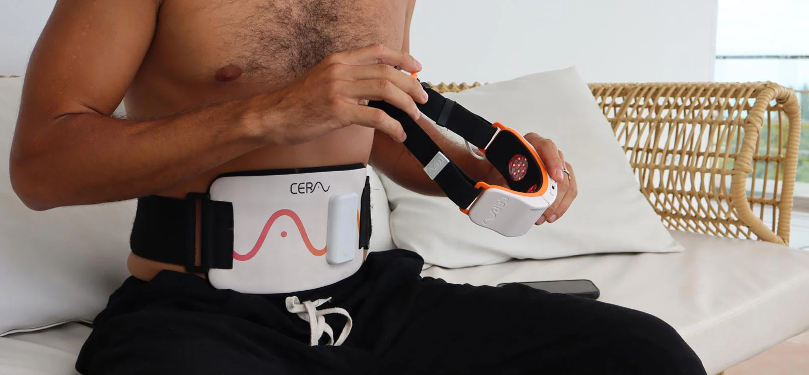 Cerathrive wellness device in use on abdomen | man wearing Cerathrive recovery belt and holding the handheld unit for targeted pain relief and muscle recovery